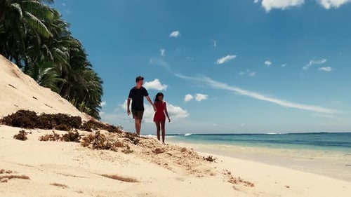 Romantic Interracial Couple Walks on Beach at Summer, Holding Hands Together