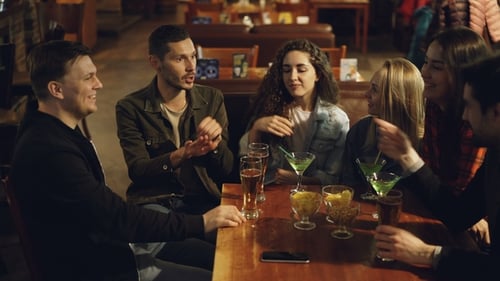 Handsome Young Man Telling Story to His Friends Sitting Together in Cafe