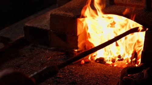 Metal Rod Placed Into Lit Furnace At Night
