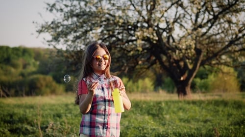 Girl Blowing Bubbles in Sunny Meadow