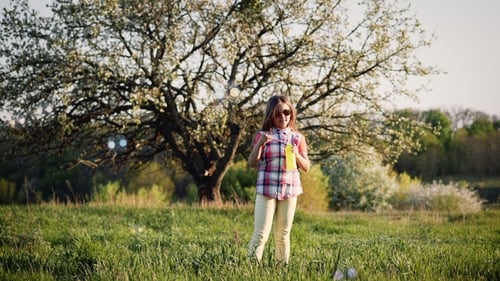 Girl Blowing Soap Bubbles in Park at Sunset