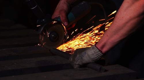 Worker Using Angle Grinder with Flying Sparks