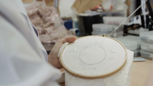 Side View of Woman Is Embroidering a Picture of a Flower Leaf on the Fabric