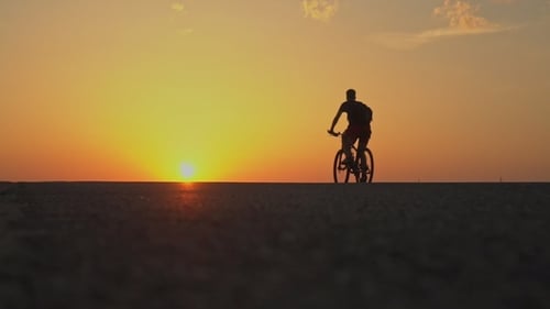 Cyclists Silhouetted Against Desert Sunrise, Golden Hour