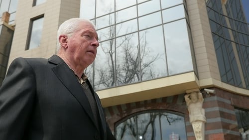 Grey-headed Man in a Business Suit Walks along a City Street in Spring