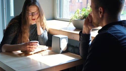 Young Couple Talking and Drinking Coffee in Cafe