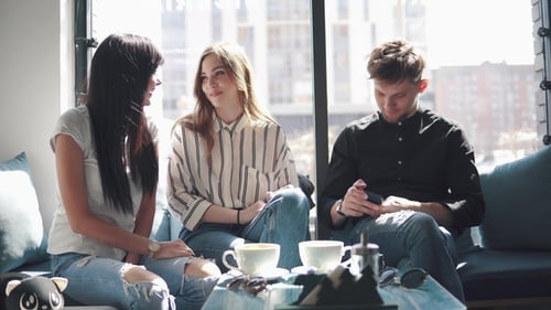A Group of Friends Have Fun Sitting in a Cafe. a Guy and Two Girls Talking and Laughing at a Table