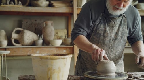 Potier senior travaillant sur la partie inférieure d'un pot en céramique sur un tour de potier tournant sur le lieu de
