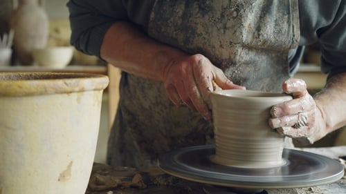 Plan de vase en céramique semi-fini tournant sur la roue du potier et les mains moulant de l'argile