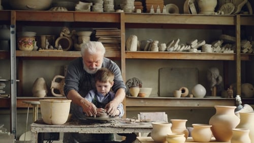 Potier professionnel grand-père aimant apprend à son petit petit-enfant à mouler de l'argile sur Potter's