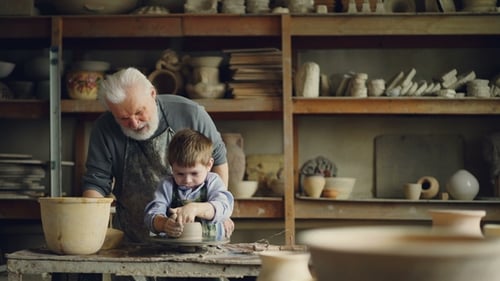 Grandfather and Child Making Pottery Together in Studio