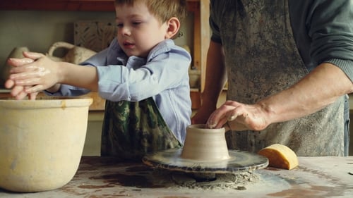 Cute Child Learning Pottery in Traditional Workshop Together with Senior Grandfather
