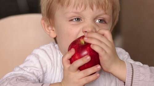 Child Eating a Red Apple Close Up