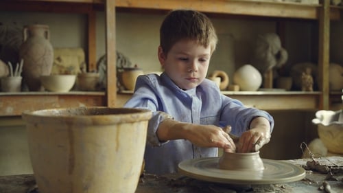 Curious Little Boy Is Working with Clay in His Father's Workshop Using Profesional Equipment