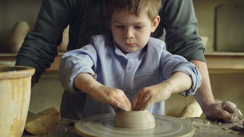 Child Learning to Mold Clay on Pottery Wheel