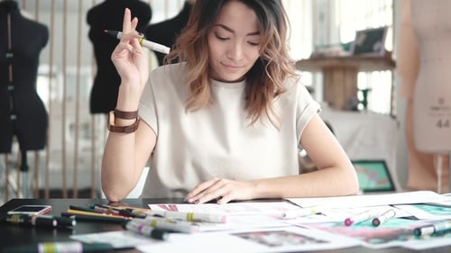 Girl Designer Clothes Makes Sketches on Paper. Young Woman Working in a Sewing Studio