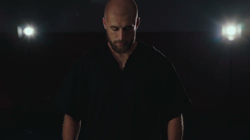 Portrait of Strong Sweaty Sportsman Looking at Camera in Darkness.