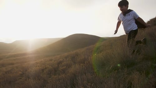 Boy Runs Down Hillside with Sword and Cape