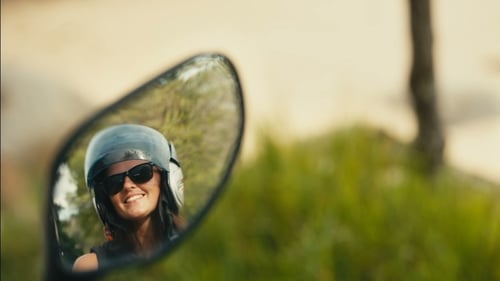 Woman reflected in motorcycle mirror