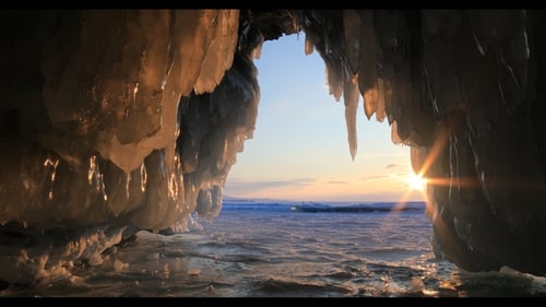 Winter Baikal. Ice Cave with Icicles at Sunset.