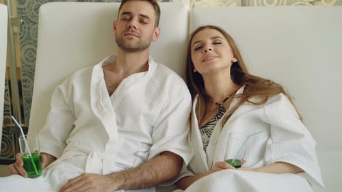 Young Married Couple Relaxing Sitting in Modern Spa Salon with Cocktail Glasses