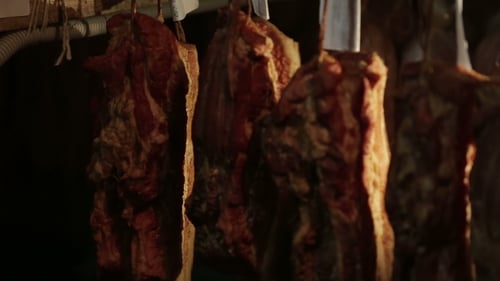 Cured Meats Hanging in a Dark Room
