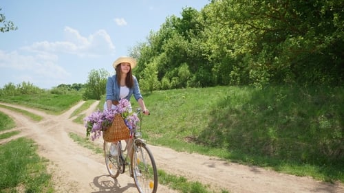 Young Woman Biking with Flowers on Rural Road