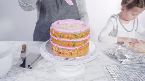 Step by step. Frosting round funfetti cake layers with pink buttercream frosting