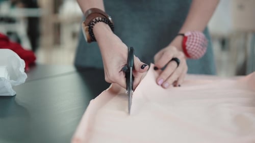 Woman Cutting Fabric with Scissors on Table