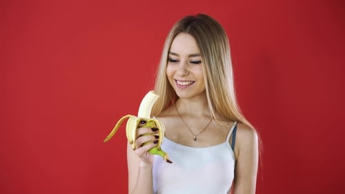 Young Woman Eating a Banana and Smiling