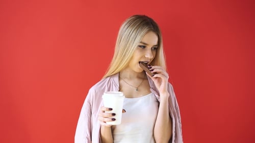 Woman Eats Chocolate and Drinks from Cup