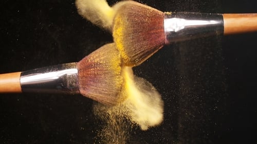 Kosmetikpinsel mit goldenem Puder auf schwarzem Hintergrund