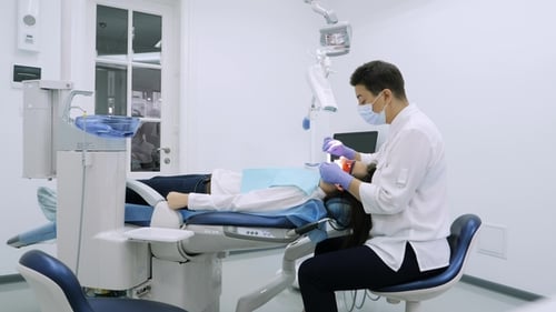 Woman Getting UV Whitening at the Dentist's Office By an Ultra Violet Machine