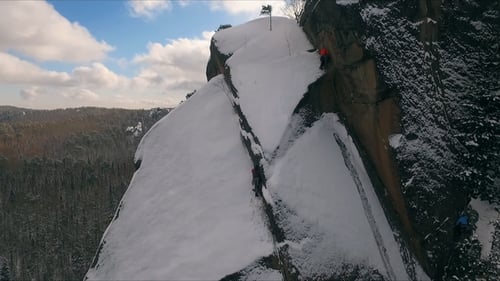 Luftaufnahme eines Kletterers, der an einem sonnigen Wintertag auf steile Klippen klettert