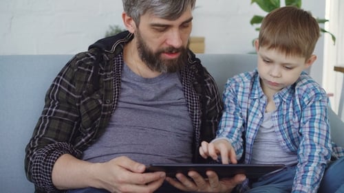 Man and Boy Using Tablet Device on Couch