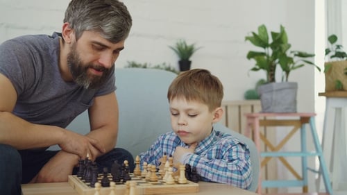 Ernstes Vorschulkind spielt Schach mit seinen Eltern und denkt über den nächsten Zug nach