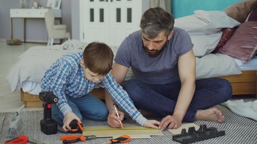 Father and Son Measuring Piece of Wood with Measure-reel Getting Ready to Construct Something