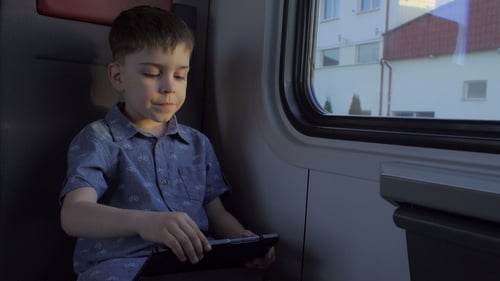 Der Junge reitet im Zug und spielt Spiele auf dem Tablet