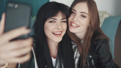 Girlfriends Do Selfie on Mobile Phone Cameras While Sitting in a Cafe