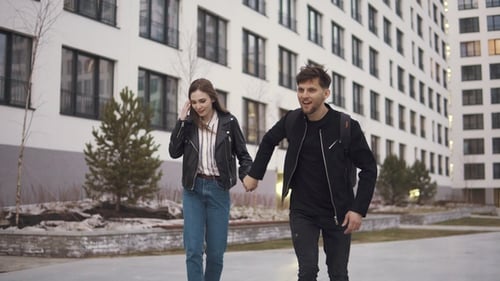 Young Man and His Girlfriend Ride Skateboards Around the City