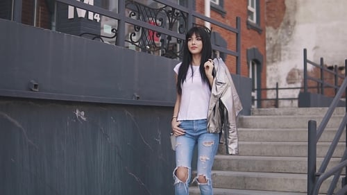 the Fashionable Girl Goes Down the Stairs. Portrait of an Attractive Girl on a Background of