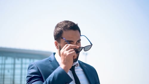Stylish Man Puts on Sunglasses Outside Modern Building