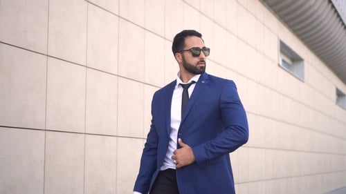 Homme d'affaires barbu marche le long du mur