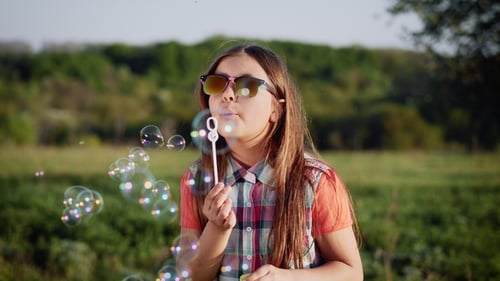 Happy Child Blowing Soap Bubbles in Spring Park