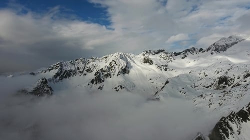 Wolken zwischen schneebedeckten Bergen