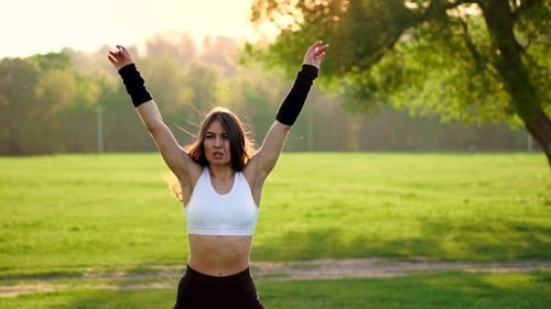 Female Fitness Instructor Doing Jumping Jacks Exercising in Green Park
