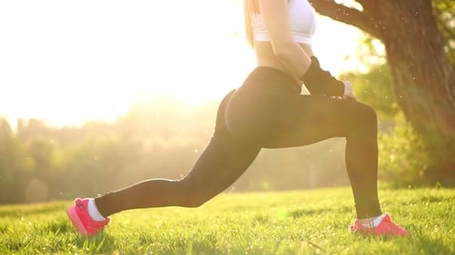Slim Athletic Woman Working out in Park Doing Knee-bounce Exercise or Lunges