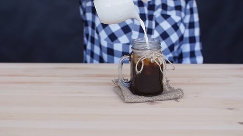 Sahne wird in einen Kaffee-Cocktail gegossen