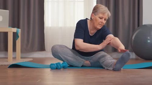 Senior Woman Stretching on Yoga Mat at Home