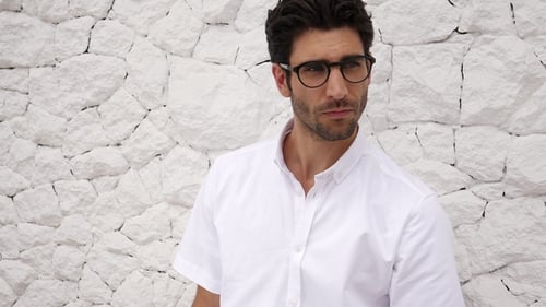 Fashionable Man Posing Against White Brick Wall